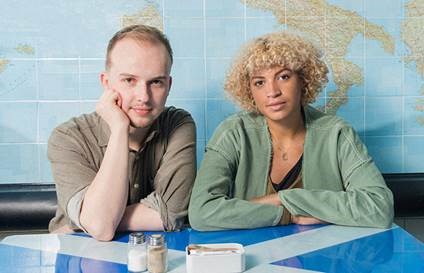 Two people staring at the camera. One with hand on cheek. Map in background.