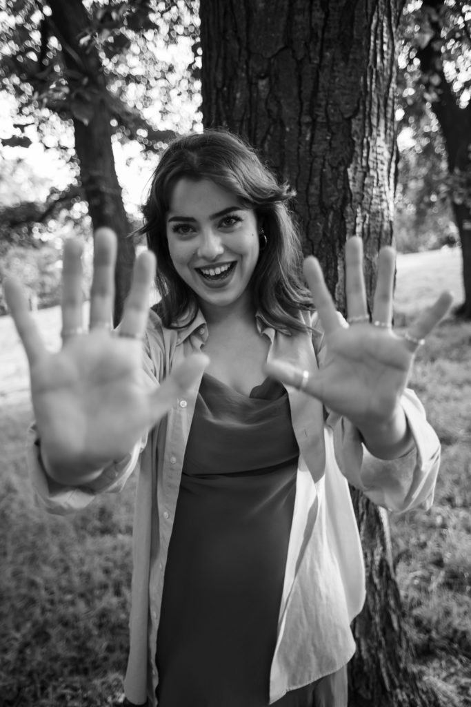 Young woman smiling to camera with jazz hands to camera