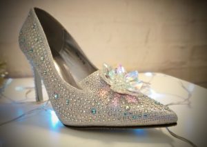 A heeled shoe on a table surrounded by fairy lights.
