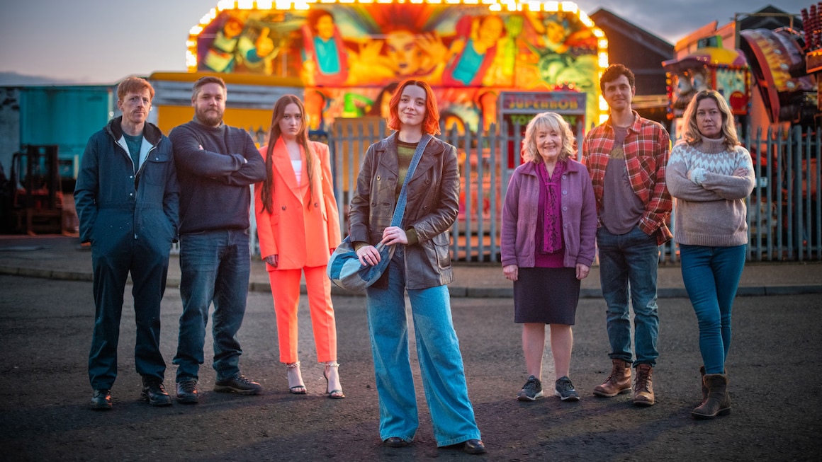 Group of people standing in front of a fairground.