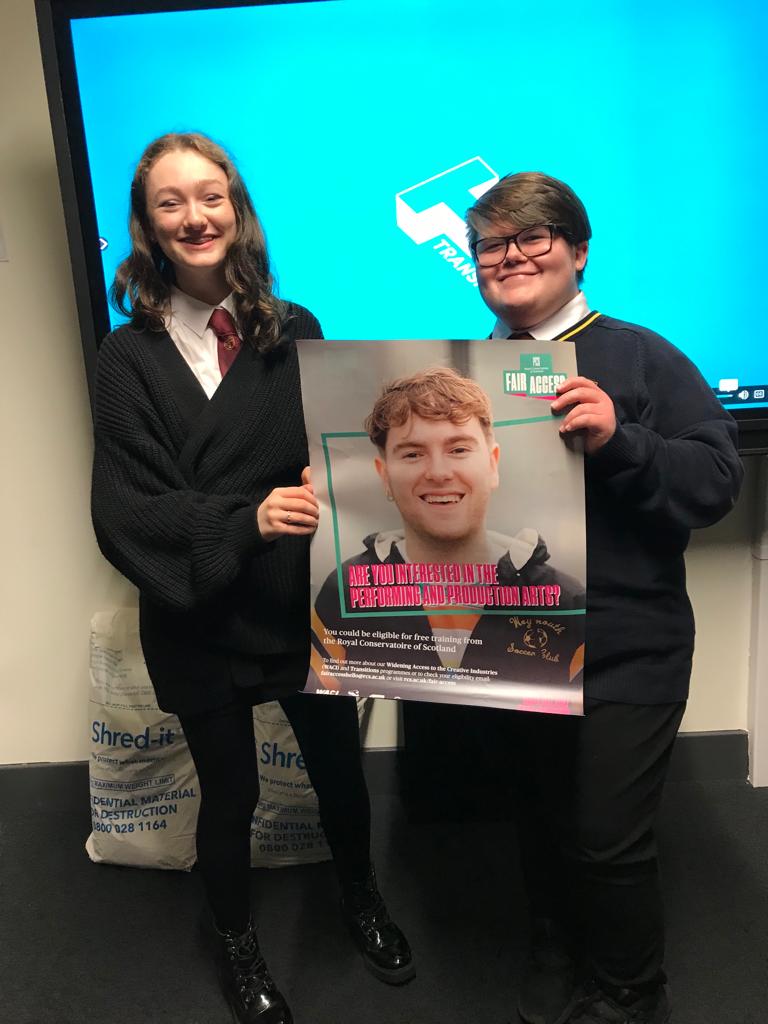 Two young people holding a poster and smiling