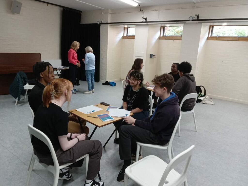 A studio classroom with people at tables chatting