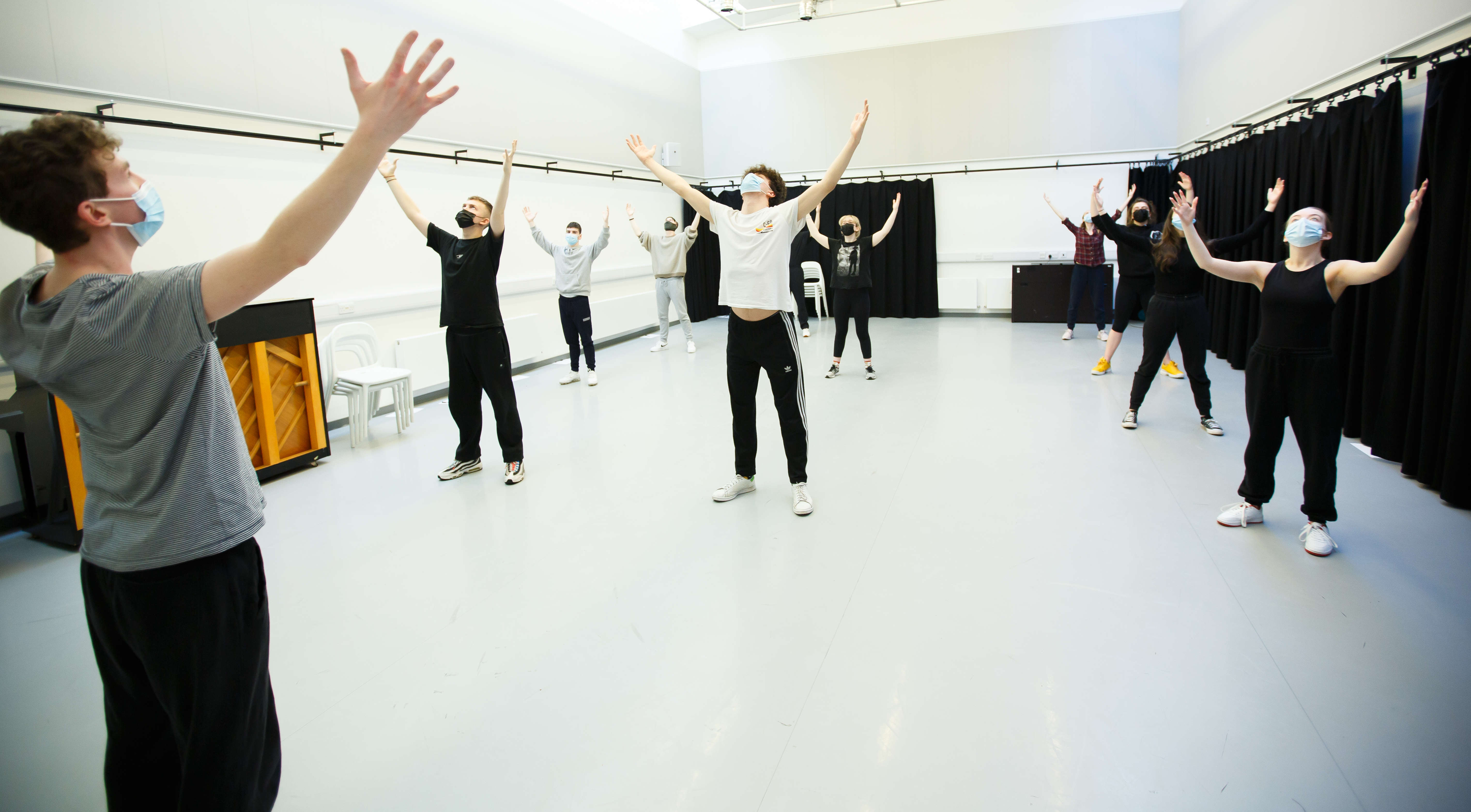 Room of people in drama studio stretching hands to the sky