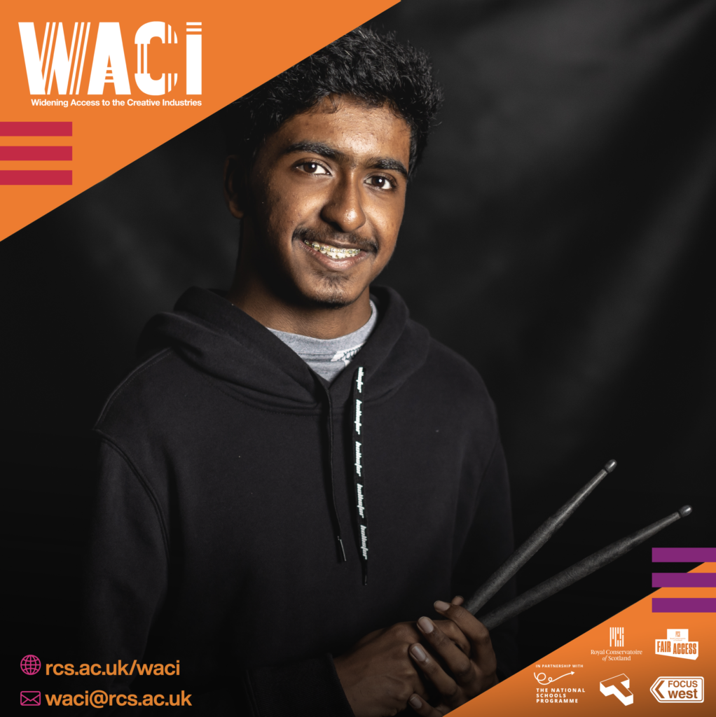 Young man with drum sticks, smiling