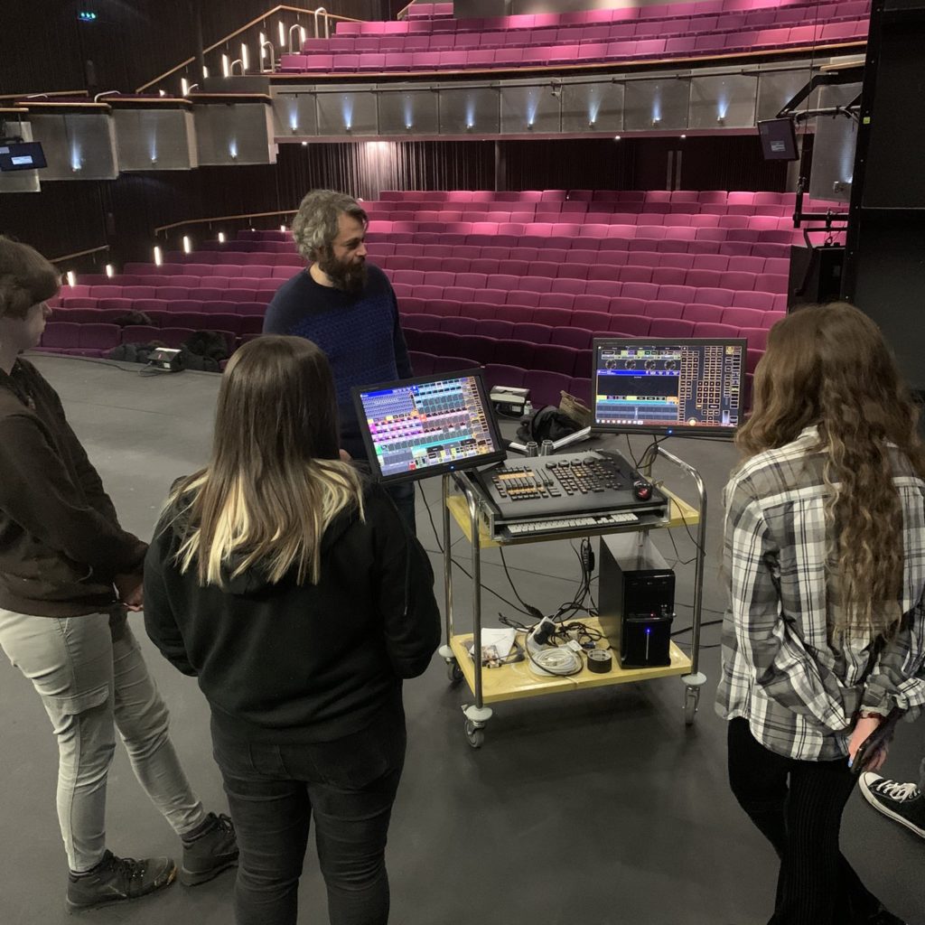 A group of young people being shown technical equipment in a theatre