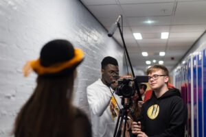 Three young people trying out a filming camera in a hallway