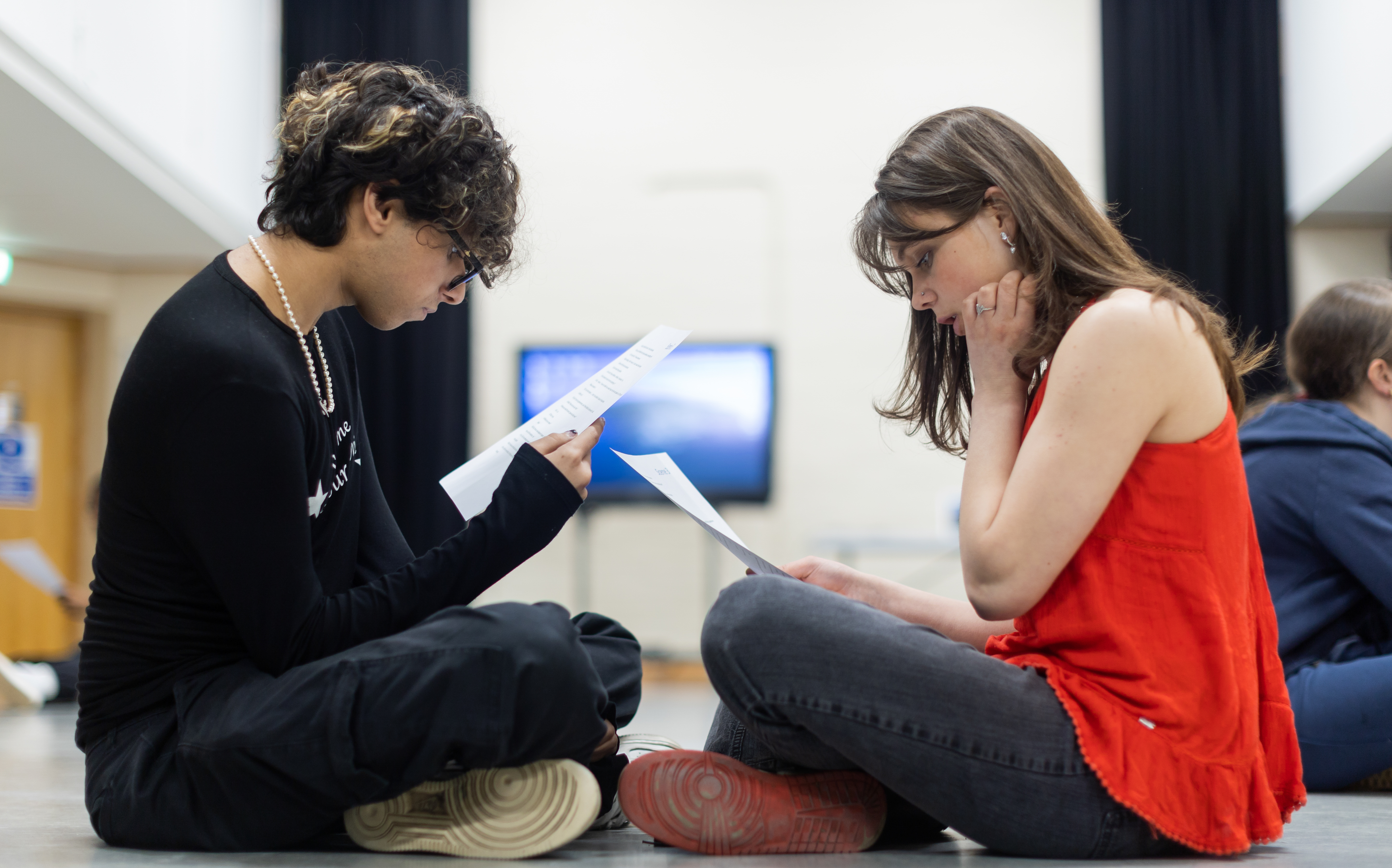 Two students sitting on floor rehearsing script