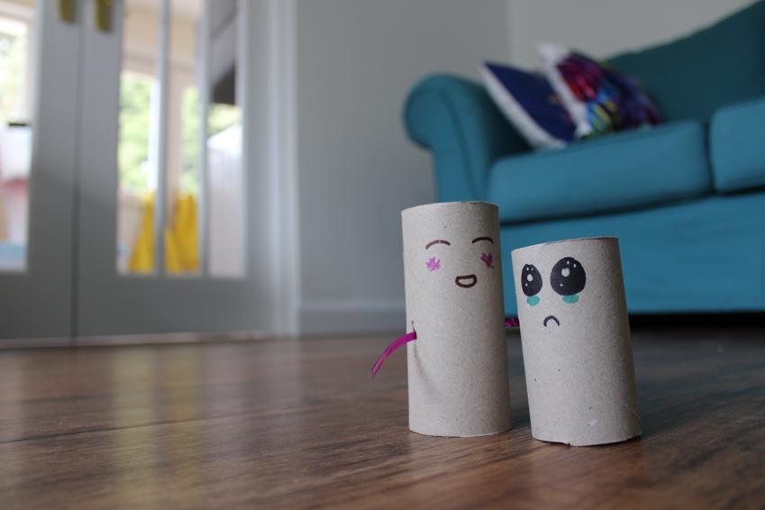 Two cardboard toilet roll holder with faces drawn on in a living room
