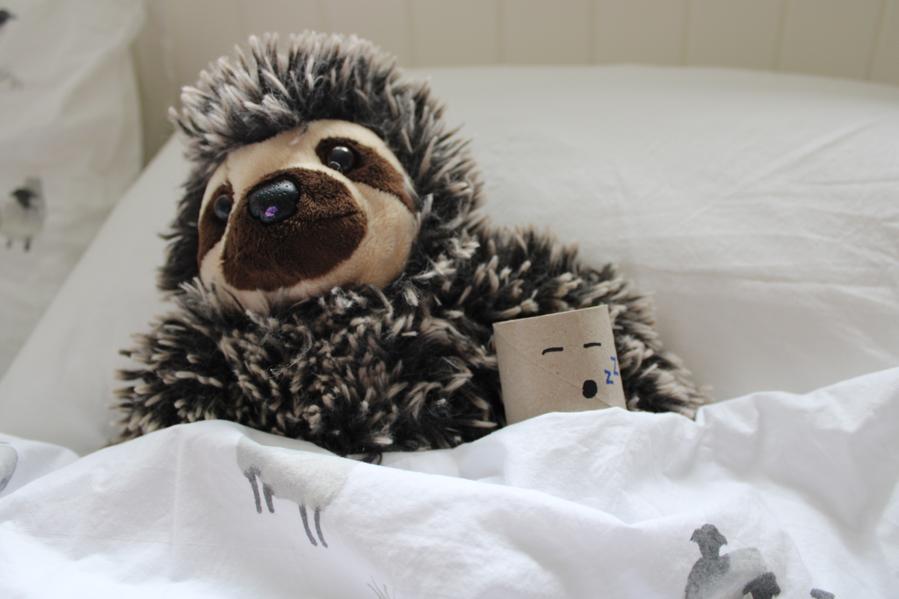 A sloth cuddly toy in bed