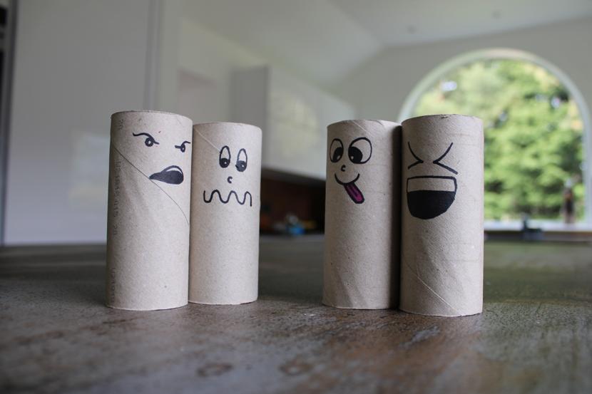 Cardboard toilet roll holder with faces drawn on